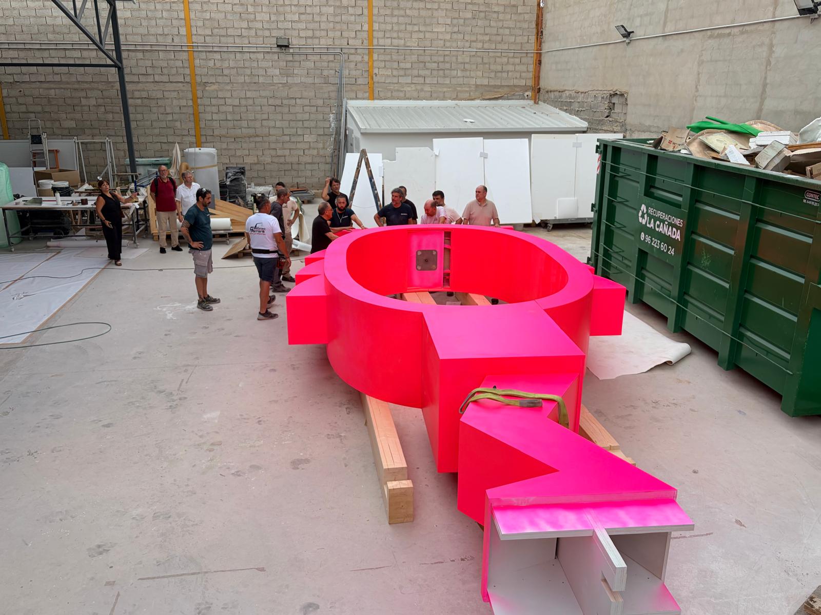 The bright pink Correfoc ring under fabrication in the Valencia workshop, surrounded by the build team